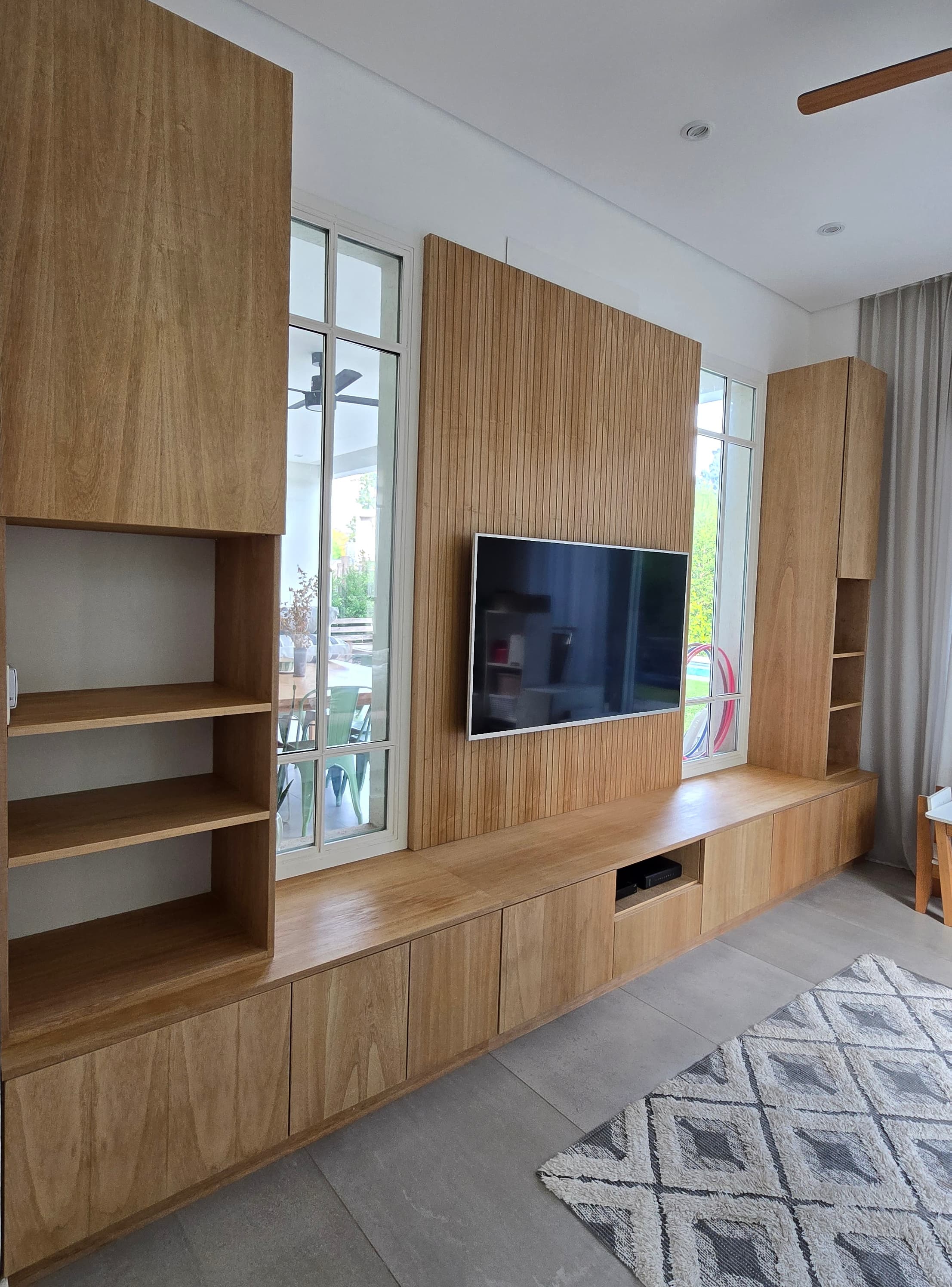 Living con pared revestida en madera, rack de TV y equipamiento integrado Woodbury
